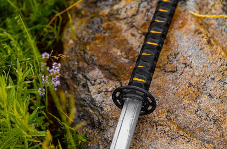 a sword laying on a rock in the grass